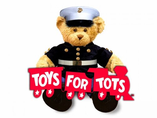 Teddy bear dressed in Marine outfit holding a red train with the words Toys for tots on it.