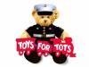 Teddy bear dressed in Marine outfit holding a red train with the words Toys for tots on it.